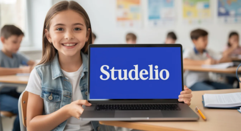 Une collégienne souriante et pleine de vie montre son ordinateur où est inscrit "Studelio" en blanc sur un fond bleu vif (#3261c5). Elle semble enthousiaste, incarnant l'esprit d'apprentissage et de partage des connaissances en français.