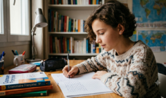 Une collégienne concentrée écrivant une dictée de français dans son cahier à son bureau